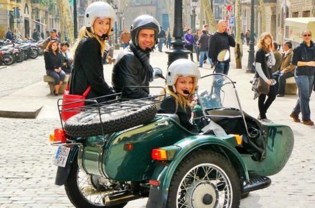 On a side car, people pose for photographs.