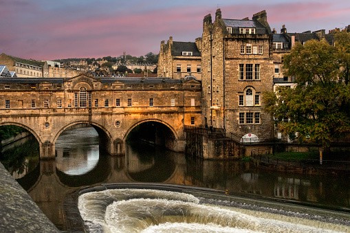 Downtown Bath, England, in the late afternoon, showing the River Avon and the old stone Pulteney Bridge crossing it
