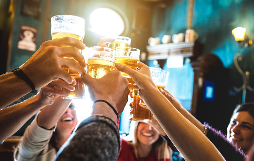 Group of happy friends drinking and toasting beer